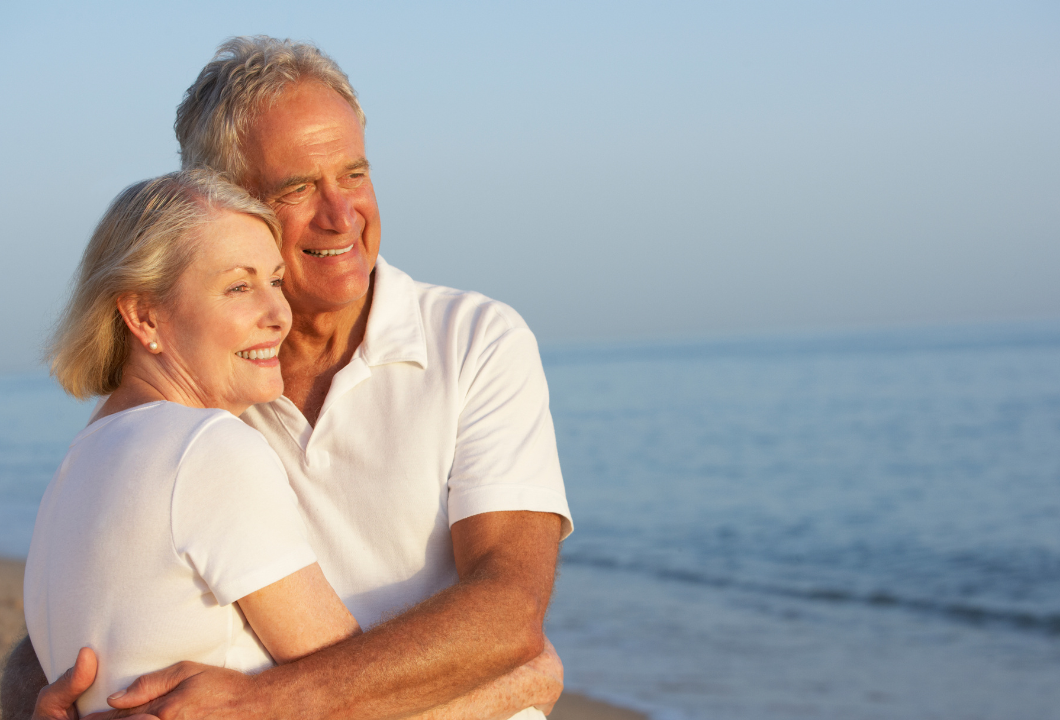 Happy couple smiling with confidence on the beach after dental tourism in Mexico