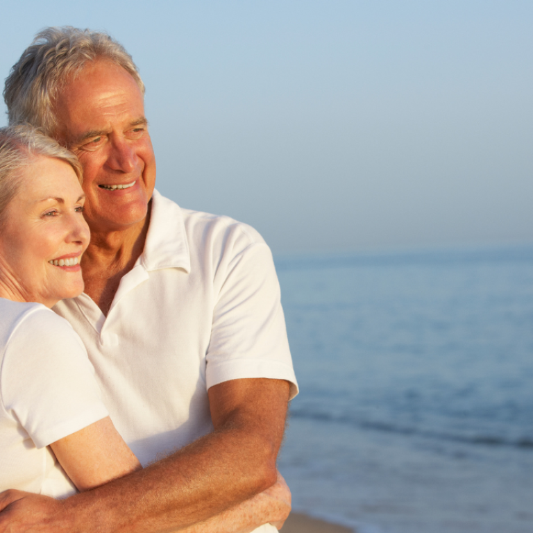 Happy couple smiling with confidence on the beach after dental tourism in Mexico
